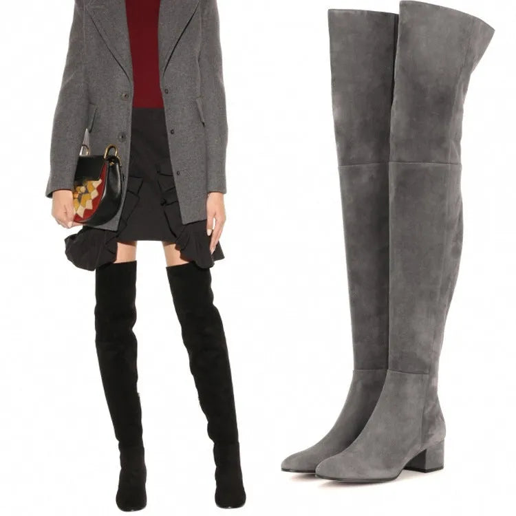 Women's grey suede over-the-knee flat boots with a pointed toe and low thick heel on a neutral background.