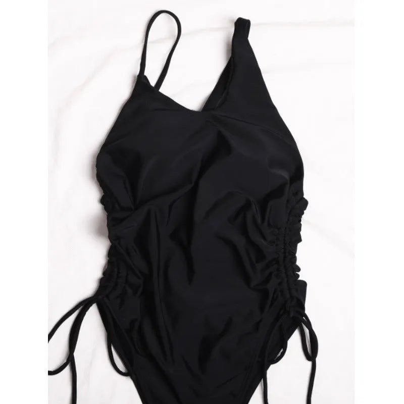 Black tight-fitting women's dress with sloping shoulders and decorative lacing detail, sleeveless design.