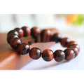 Wooden Tigereye bracelet with Lightning Cat's Eye design on wrist, showing geometric round beads.