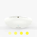 White coloured rectangular white noise sleep aid machine on a wooden surface, showing volume dial and control buttons.