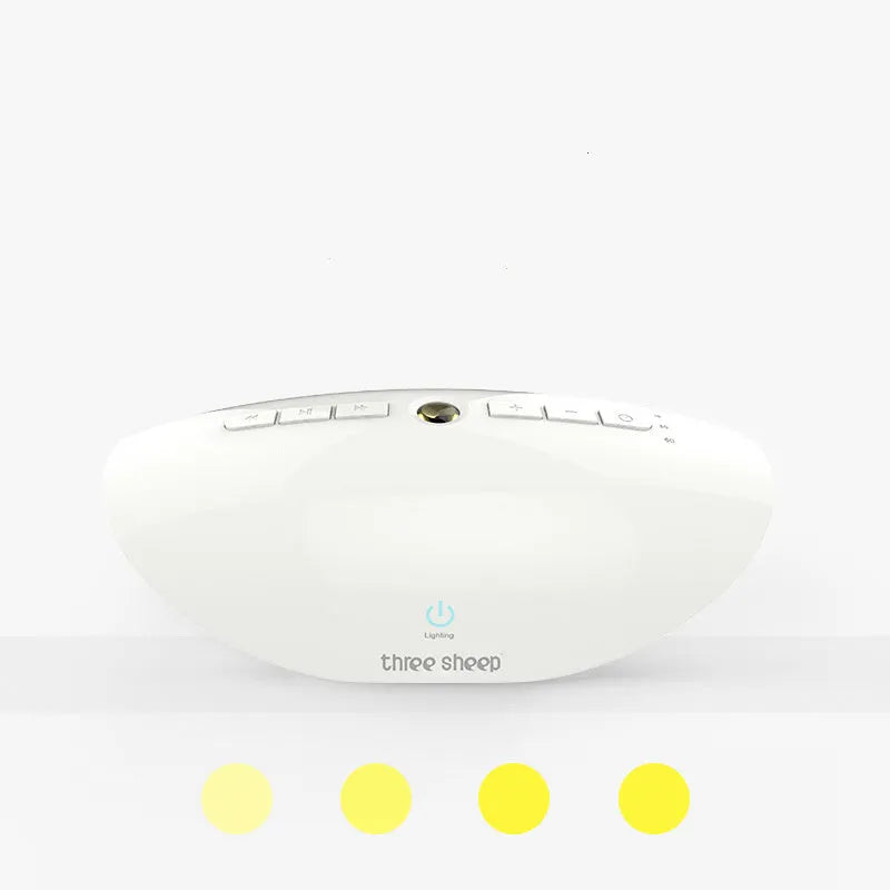White coloured rectangular white noise sleep aid machine on a wooden surface, showing volume dial and control buttons.