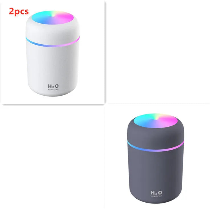 Pink USB mini humidifier with colourful lights on wooden desk