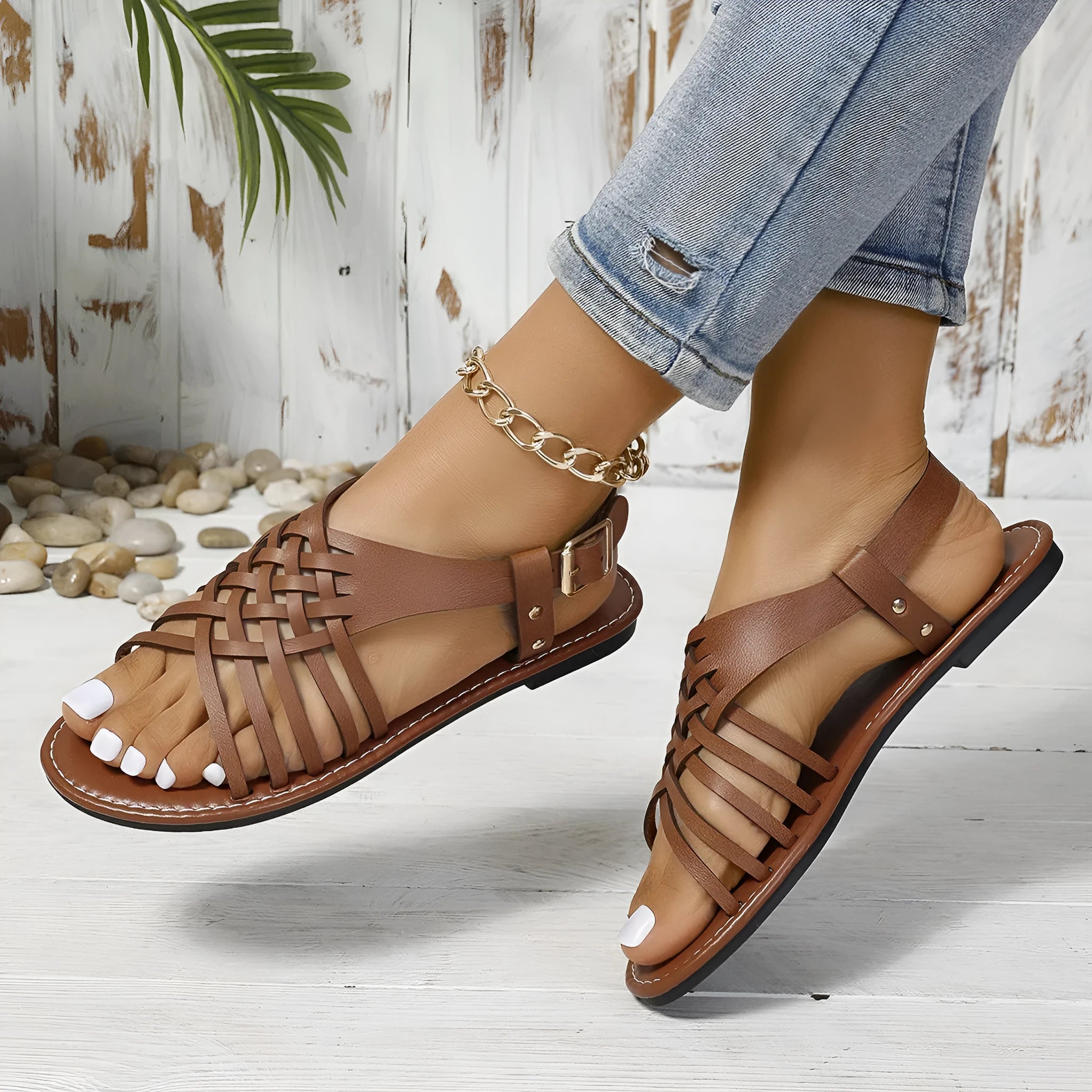 Black Roman style beach slippers with open toe, cross straps, and a flat buckle fastening