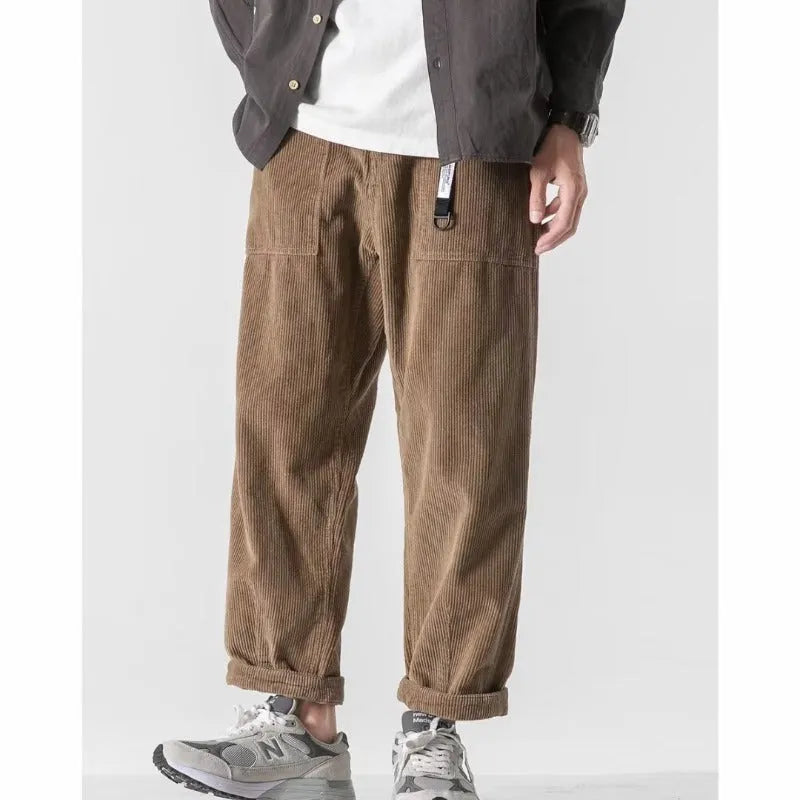 Man wearing loose straight leg tapered trousers in dark grey, showing relaxed fit and straight leg opening.