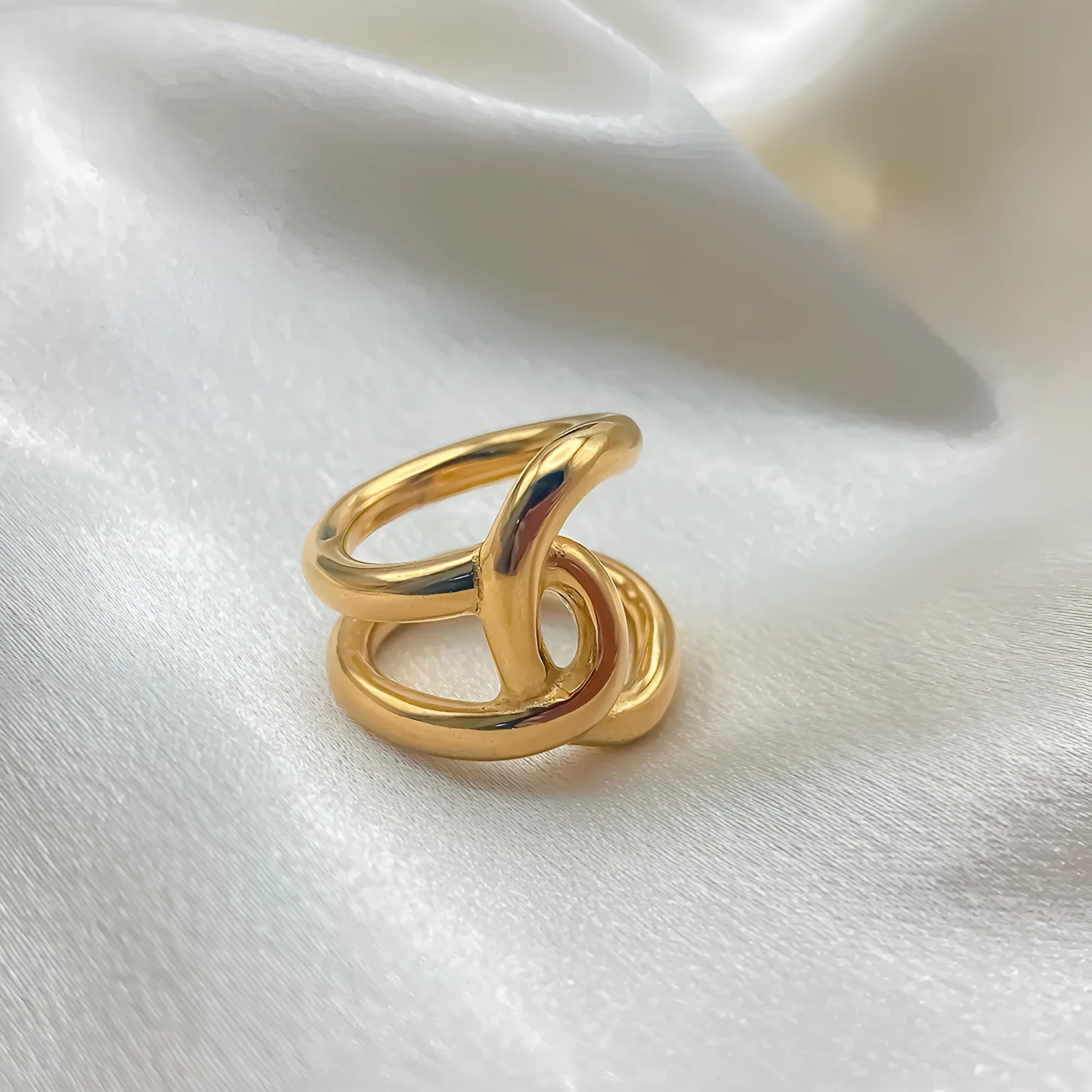 Women's stainless steel adjustable knot ring in geometric U-shape, shown in gold and steel colour finishes.