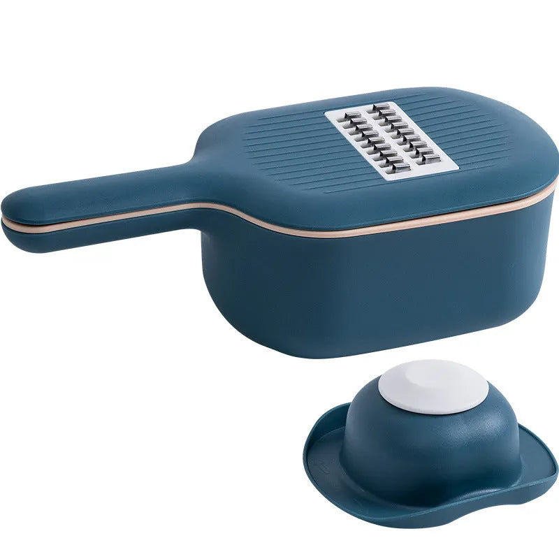 Dark blue manual vegetable cutter with four stainless steel blades, a hand protection guard, and a drain basket on a kitchen counter.