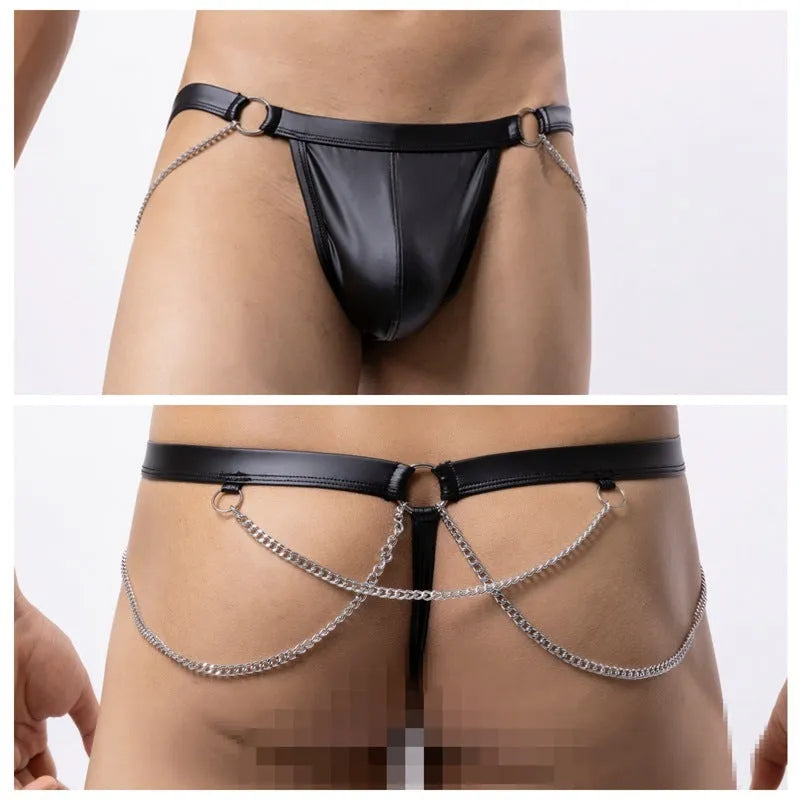 Black men's patent leather thong underwear with metal chain decoration on a grey background.