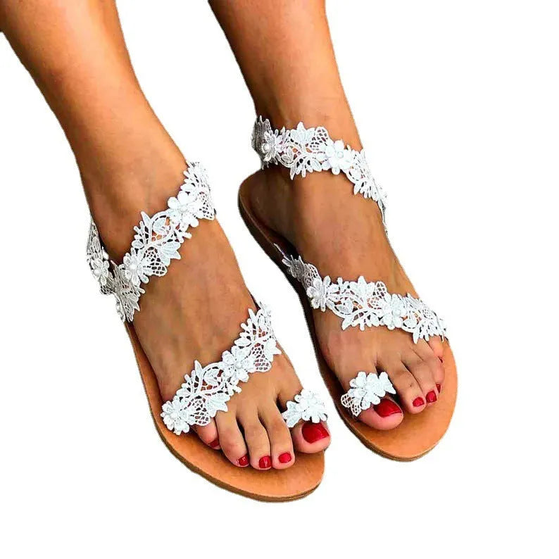 White women's slip-on flat shoes with floral and rhinestone decoration on the upper.
