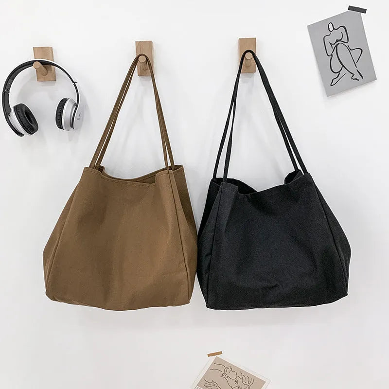 Women's black canvas shopping handbag with double shoulder straps showing internal mobile phone pocket