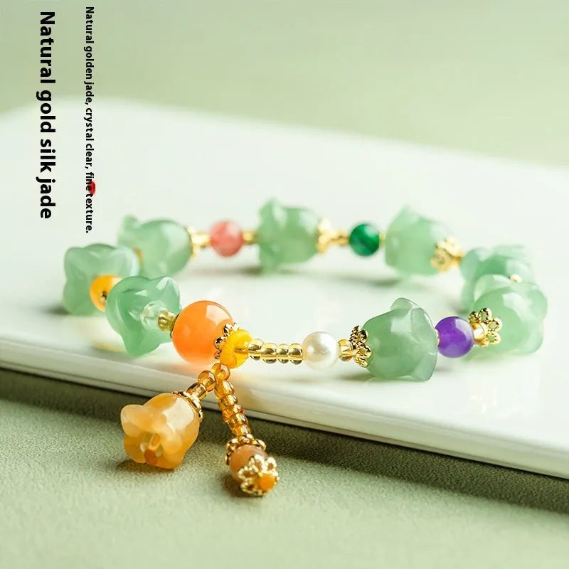 Close-up of a women's jade bracelet with hand-carved orchid-shaped beads on a wrist.