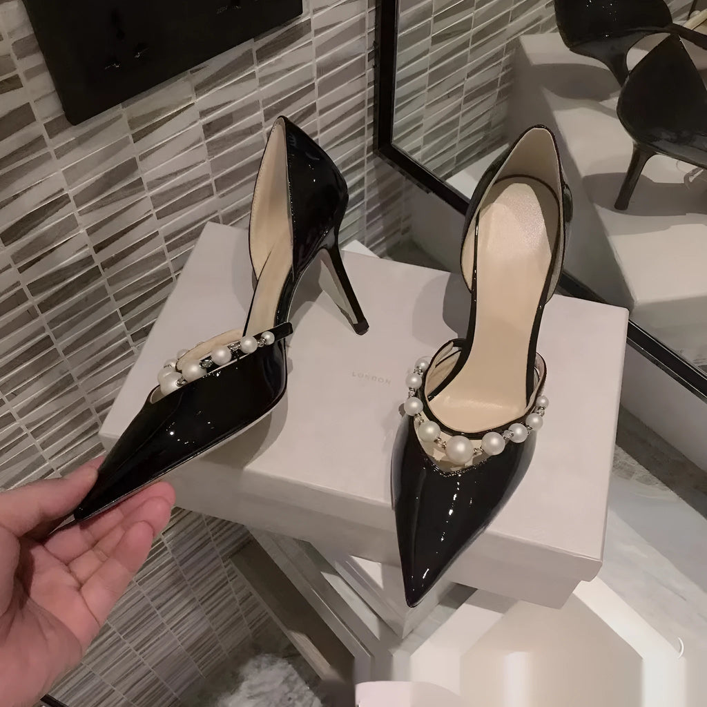 Women's black patent leather pointed stiletto heels with pearl decoration on the upper.