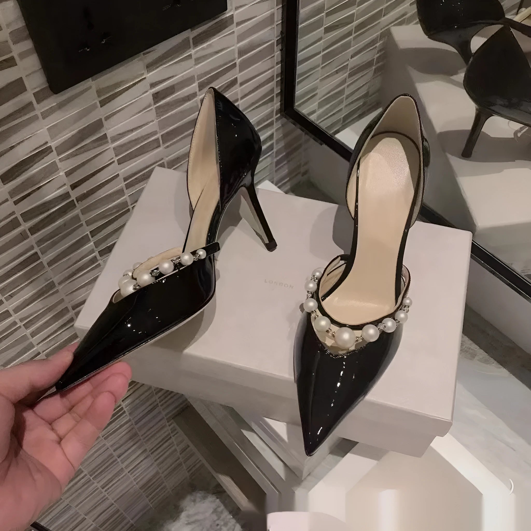 Women's black patent leather pointed stiletto heels with pearl decoration on the upper.