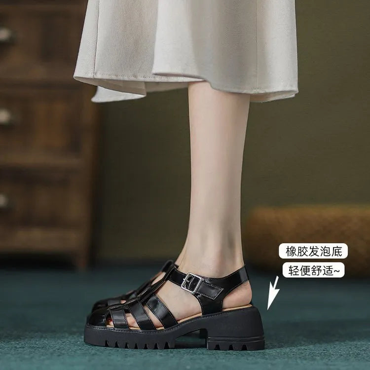 Women's black retro platform sandals with closed toe, hollow out holes, and a silver buckle closure on a chunky rubber heel.