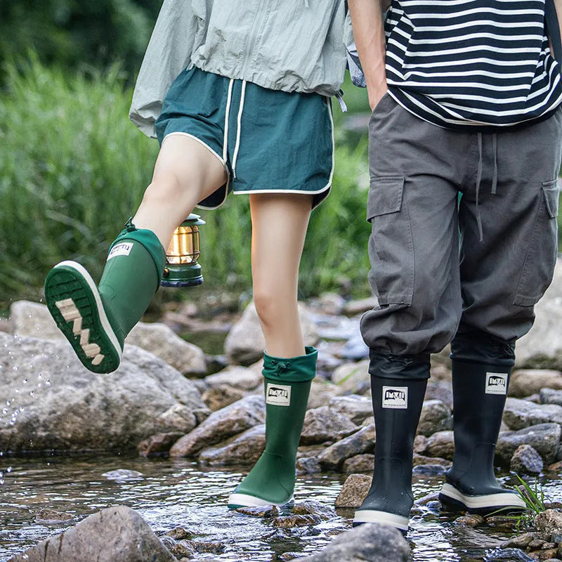 A pair of high tube PVC rain boots in a solid colour, shown on a non-slip sole.