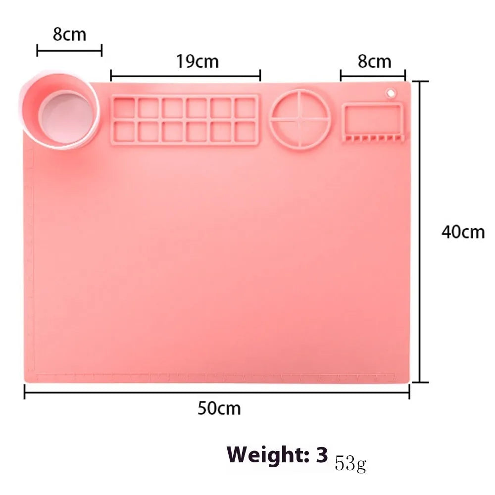 Light blue silicone painting mat with two integrated round bowls, laid flat on a wooden table.