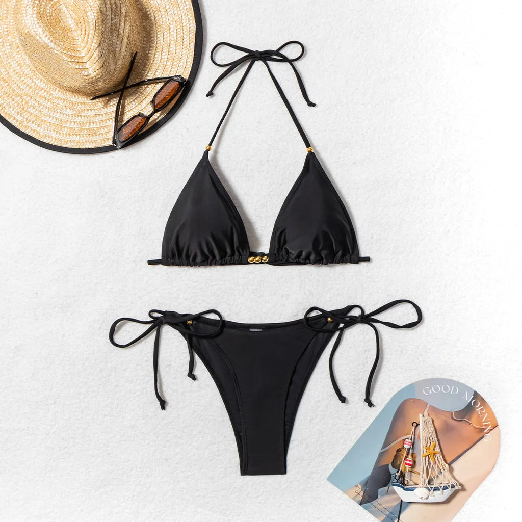 Black women's bikini swimsuit with metal bead detail and split design.