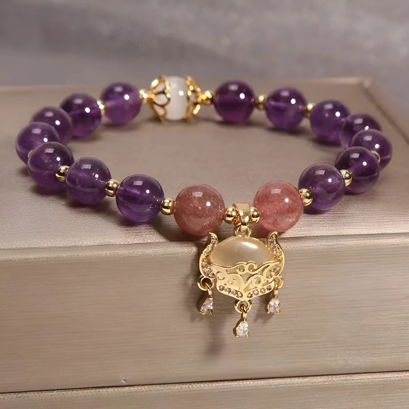 Close-up of a handmade copper bracelet for women with a drop-shaped longevity lock charm, Ruyi element, amethyst stones, and gold accents.