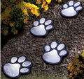 Black solar-powered bear paw-shaped garden light with ground stake and solar panel.