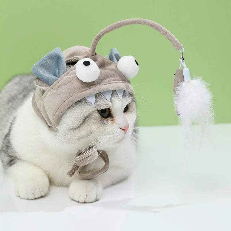 Grey head-mounted cat toy with feather and big-eye fish attachments on adjustable elastic band
