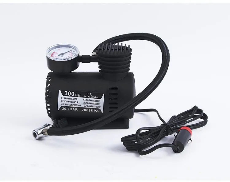 Black portable 12V mini car air compressor with pressure gauge, hose, and two nozzle adapters on grey background