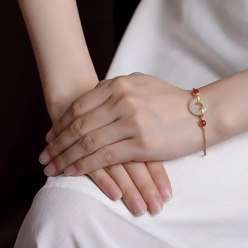 Close-up of a sterling silver bracelet with a gold-plated peace buckle holding inlaid natural Hetian jade.