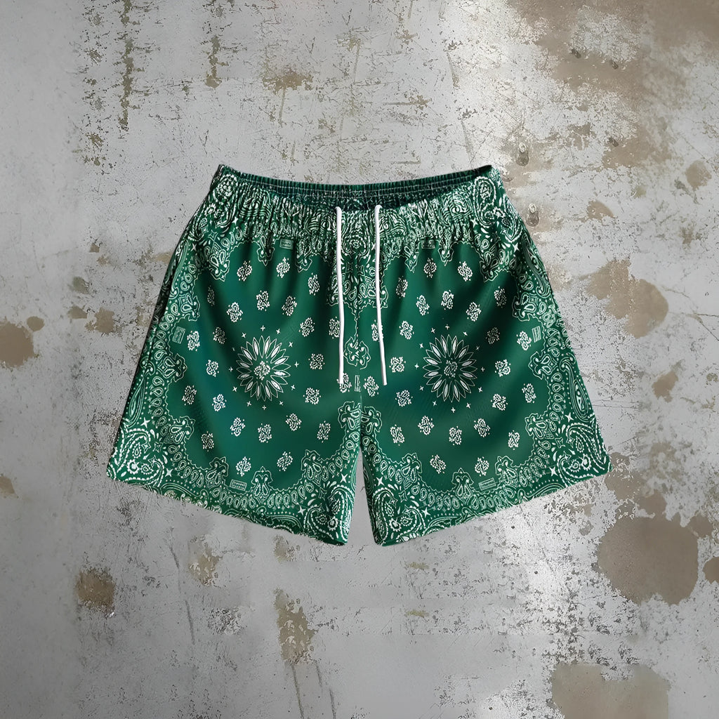 Man wearing loose-fitting quick-dry beach shorts with a digital print pattern in a summer setting.
