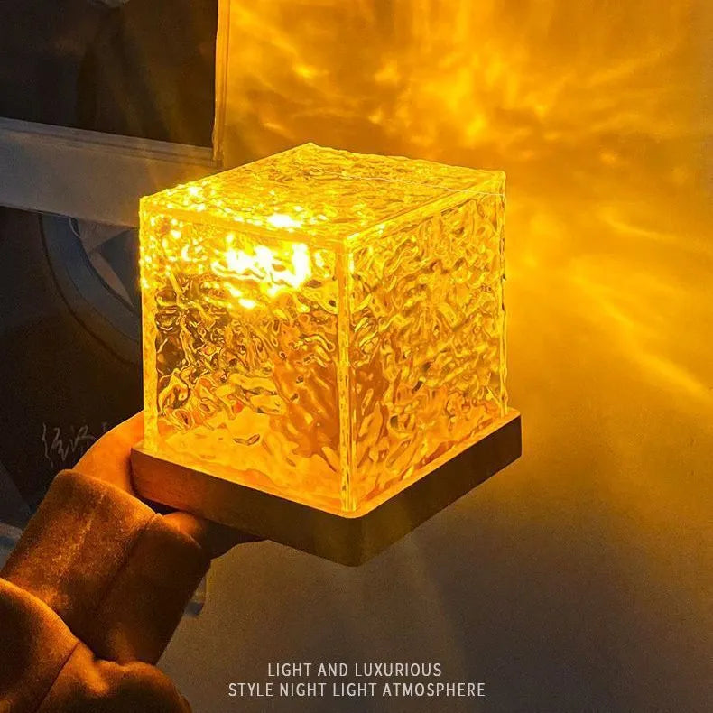 Square crystal LED table lamp projecting blue water ripple light patterns on a wall.