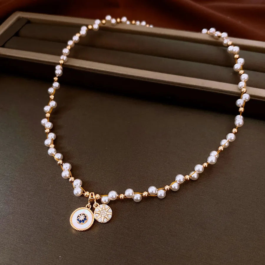 Gold and white electroplated necklace with round pearl pendant and zircon detailing on clavicle chain