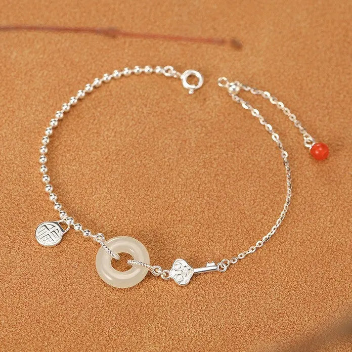 Women's silver bracelet with a geometric Hetian jade peace buckle charm on a chain.