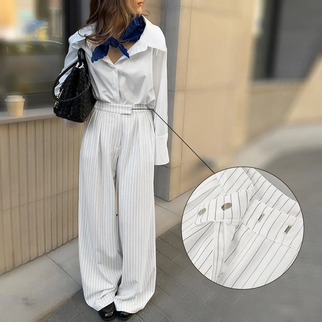 White striped loose-fit wide-leg trousers with a front zipper closure on a model.
