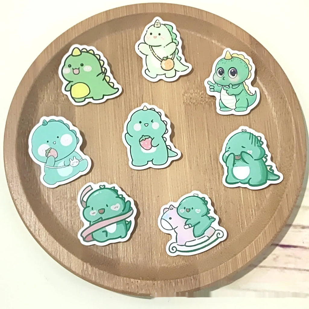 Cartoon dinosaur acrylic badge brooch with printed design and pin fastening, shown in one of twelve colour styles