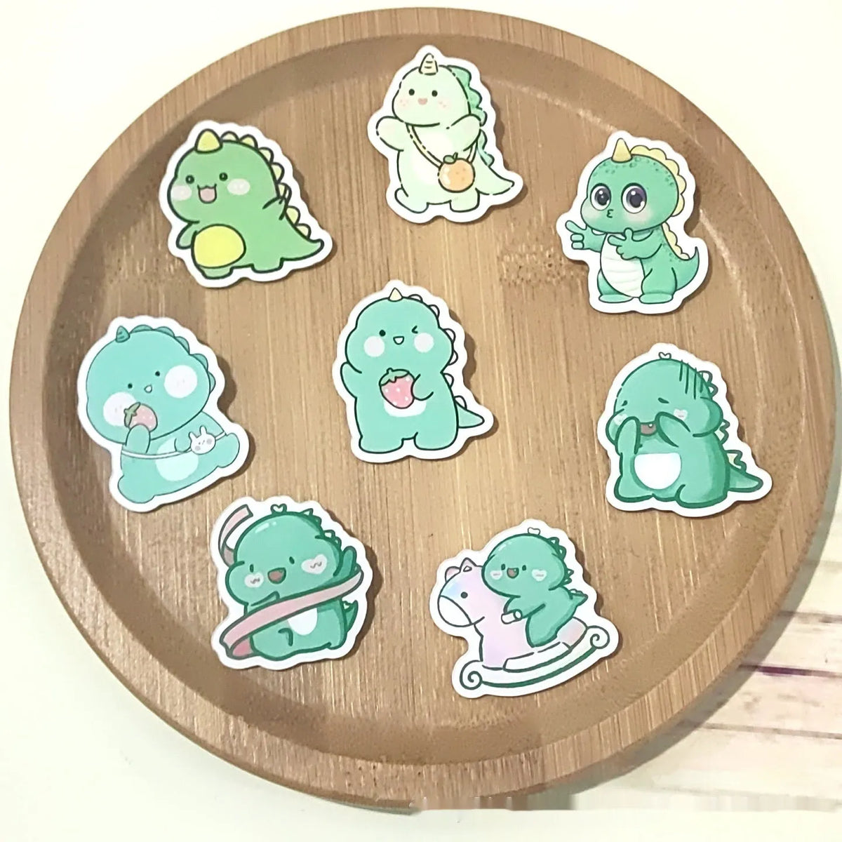 Cartoon dinosaur acrylic badge brooch with printed design and pin fastening, shown in one of twelve colour styles