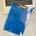 Transparent A4 clipboard with metal clip, shown in blue colour on a wooden desk.