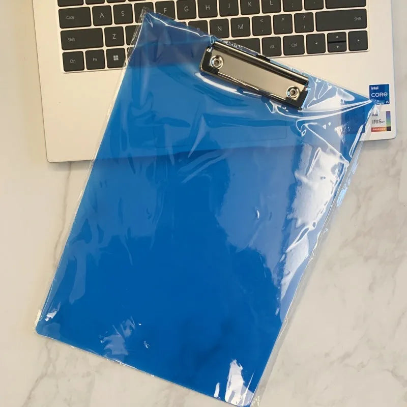 Transparent A4 clipboard with metal clip, shown in blue colour on a wooden desk.