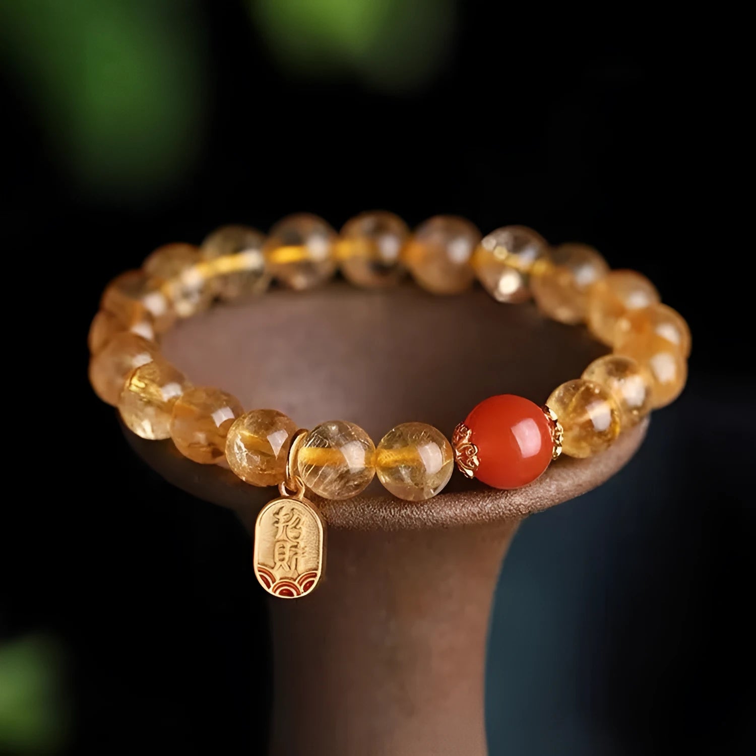 Red agate natural stone bracelet with gold and ruby accent beads on a wrist.