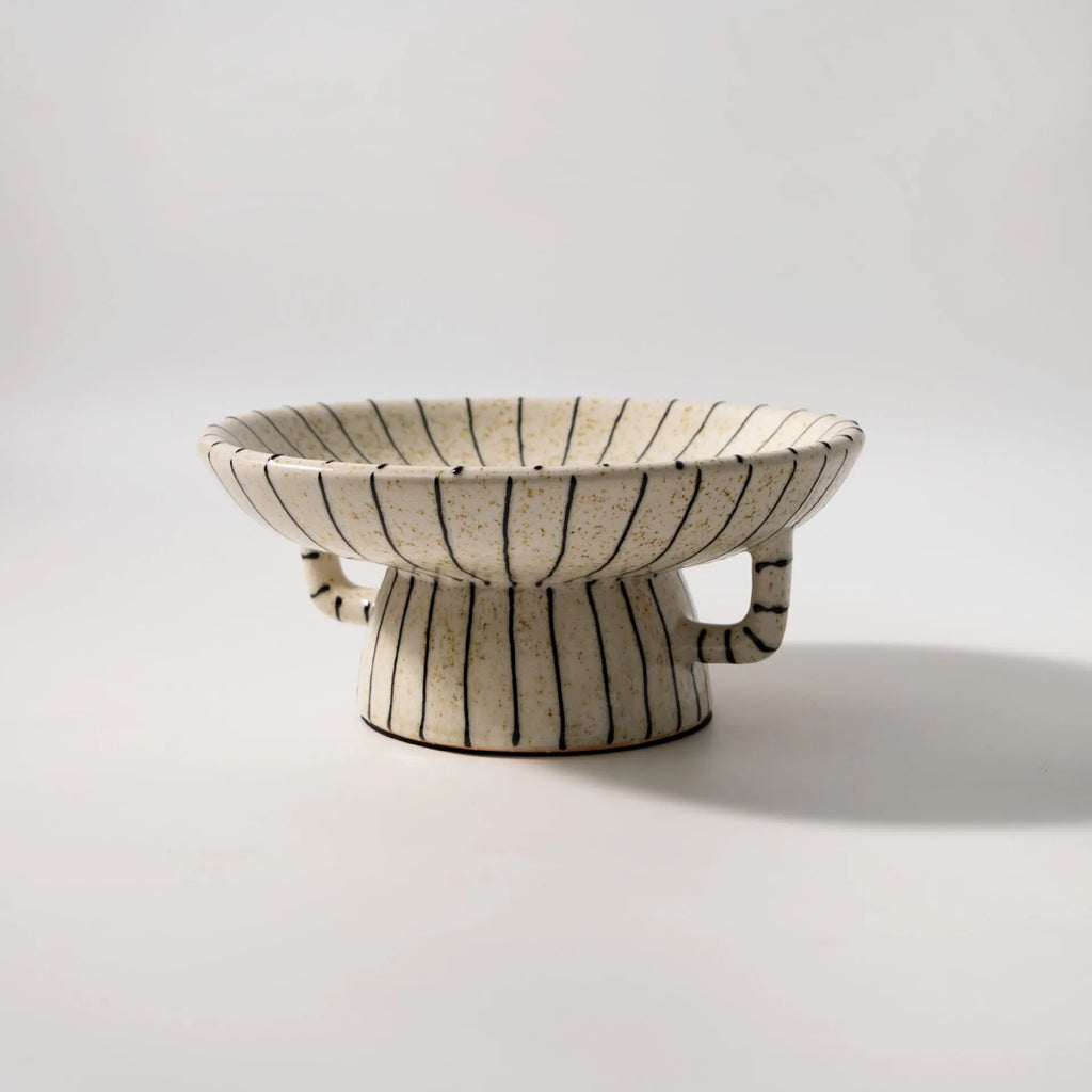 Black and white striped synthetic resin fruit plate on a plain surface.