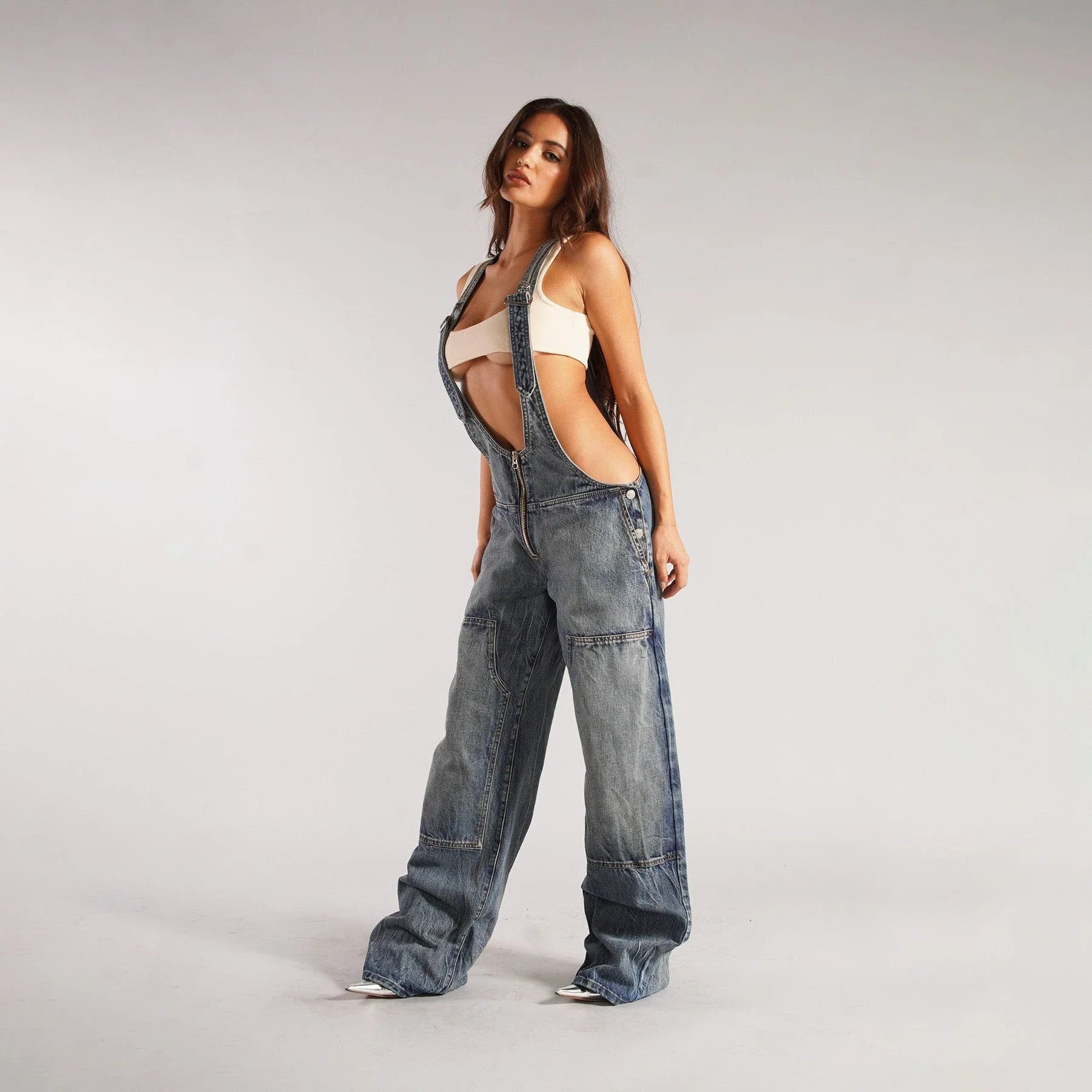 Stylish Y2K-inspired denim suspender jumpsuit with pockets, featuring a relaxed wide-leg silhouette and adjustable straps for a customized fit.