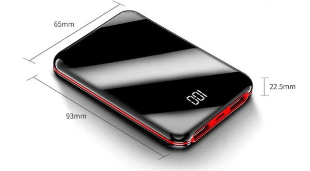 Black mini power bank with digital LCD screen showing battery percentage, next to a smartphone.
