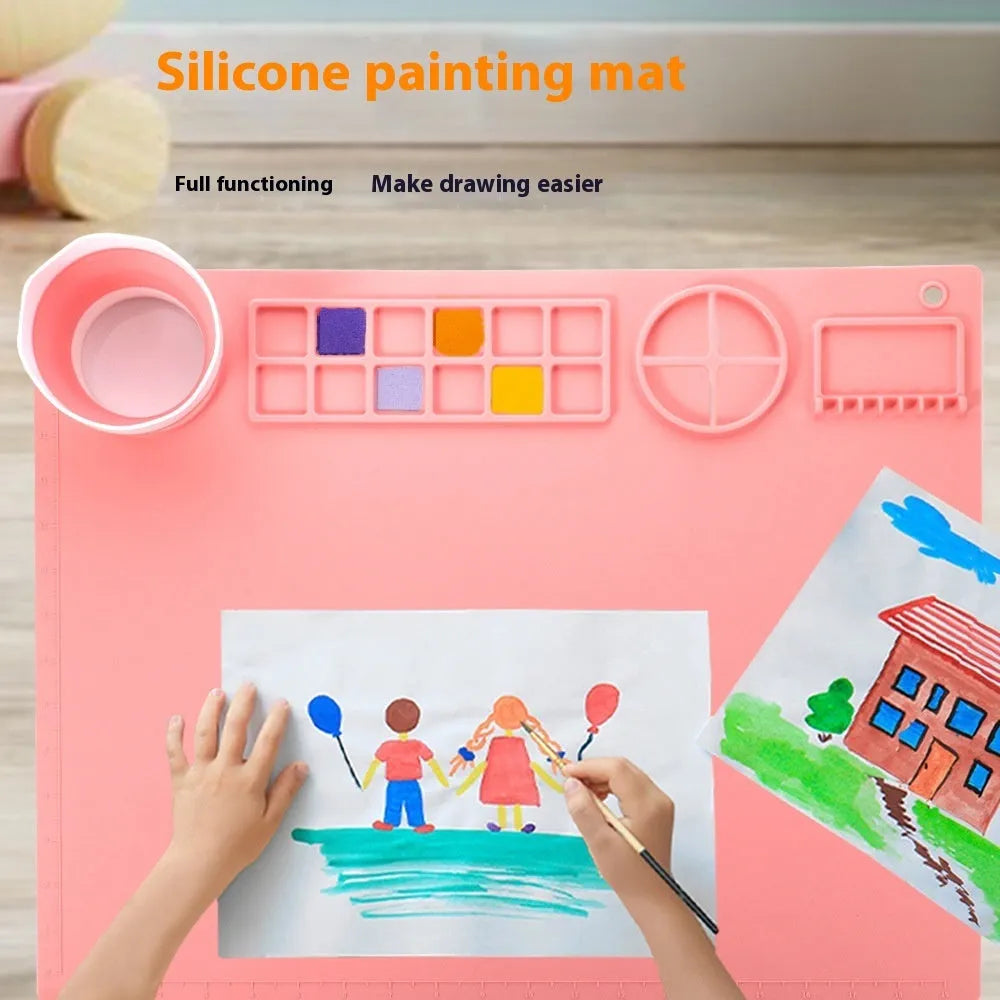 Light blue silicone painting mat with two integrated round bowls, laid flat on a wooden table.