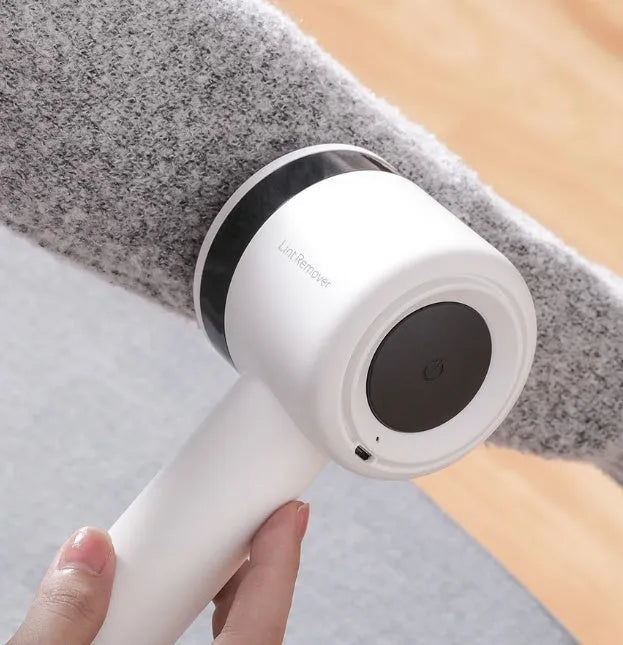 White rechargeable lint remover with hidden hair collection container and detachable three-blade head on white background