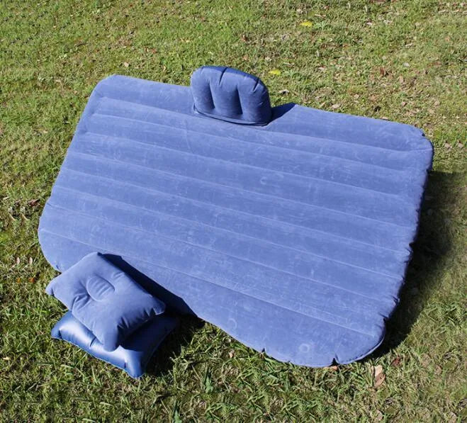 Inflatable car bed with flocking material shown in black colour, folded beside pillows and storage bag