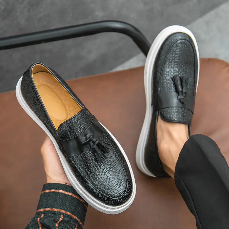 Men's black casual leather shoes with fringe detail on round toe, showing low heel profile.