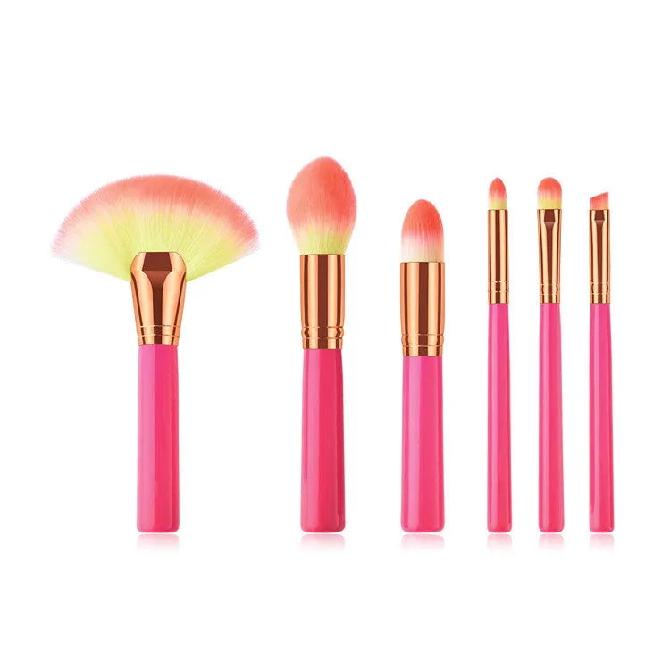 Pink cosmetic makeup brush set with wooden handles and synthetic bristles laid out on a surface