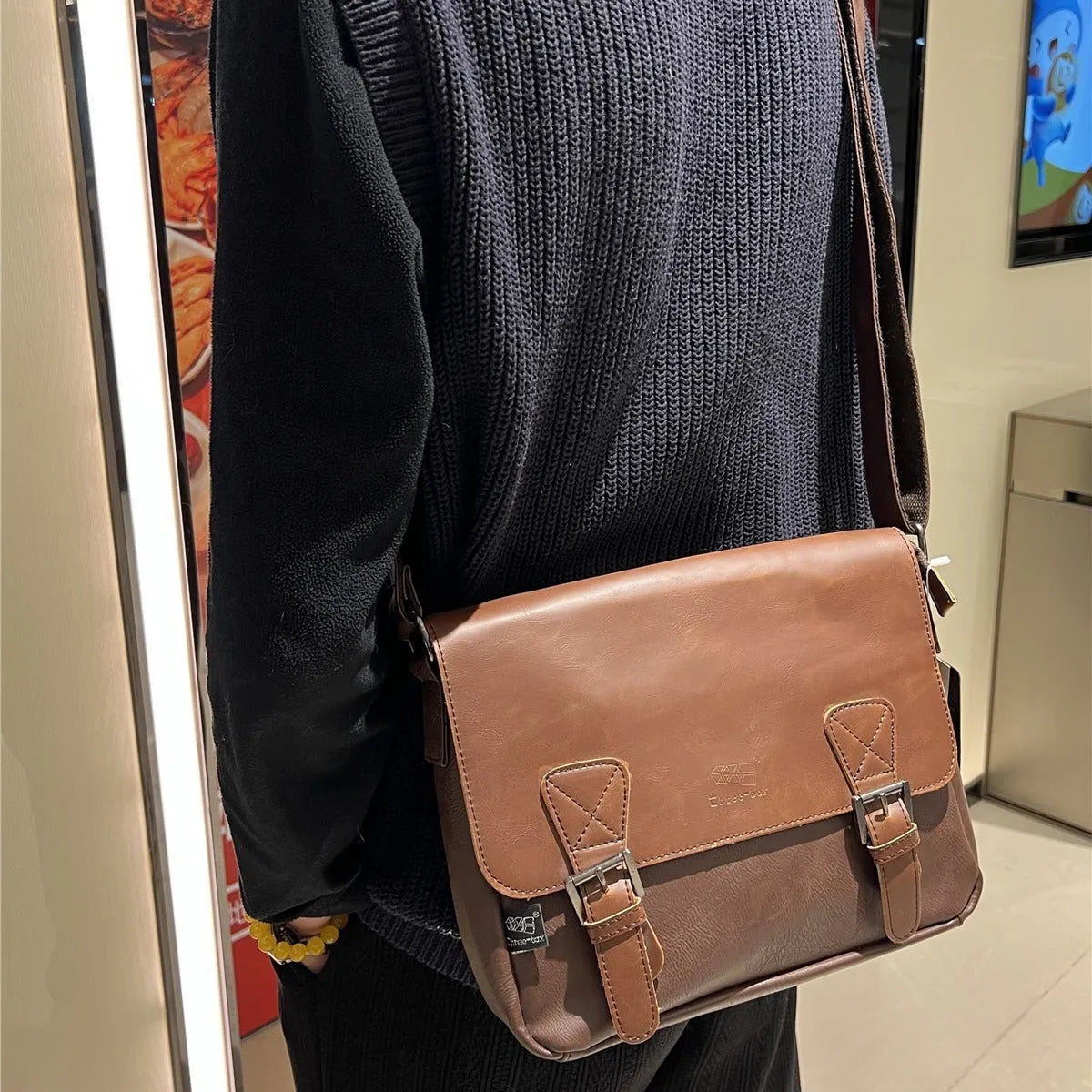 Retro men's messenger bag in light brown PU material with shoulder strap on neutral background