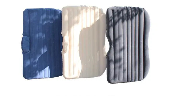 Inflatable car bed with flocking material shown in black colour, folded beside pillows and storage bag