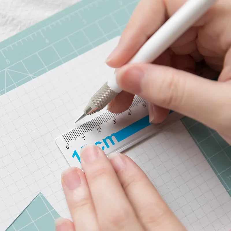 Art pen knife cutting board set showing coloured plastic mat, metal ruler, knife, sharpener, and blade.