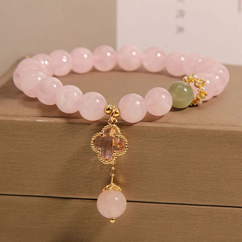 Pink crystal women's bracelet with a four-leaf clover pendant and sparkling rhinestone details.