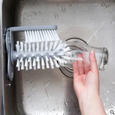 Grey rotating cup brush with two suction cups for wall mounting, shown cleaning a glass