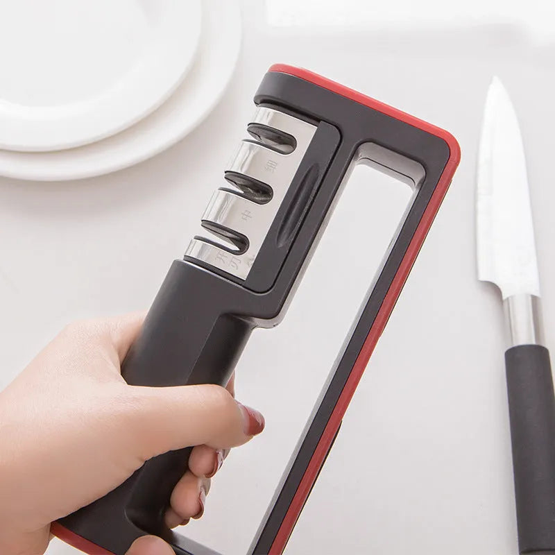 Black and red three-stage manual knife sharpener with rubber feet on base