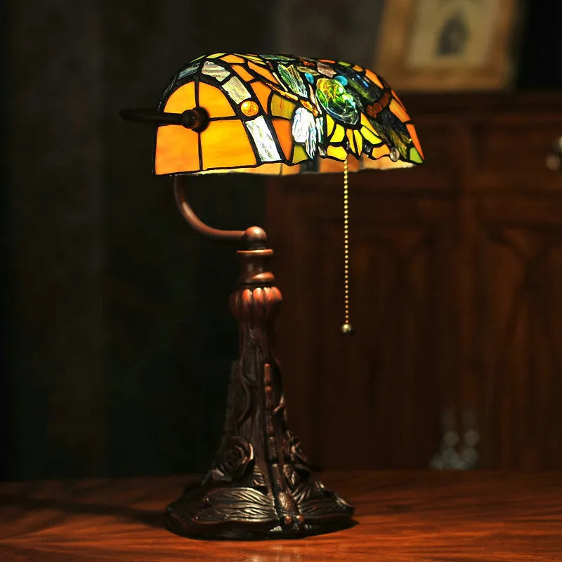 Tiffany stained glass table lamp with coloured lampshade and resin base on a desk